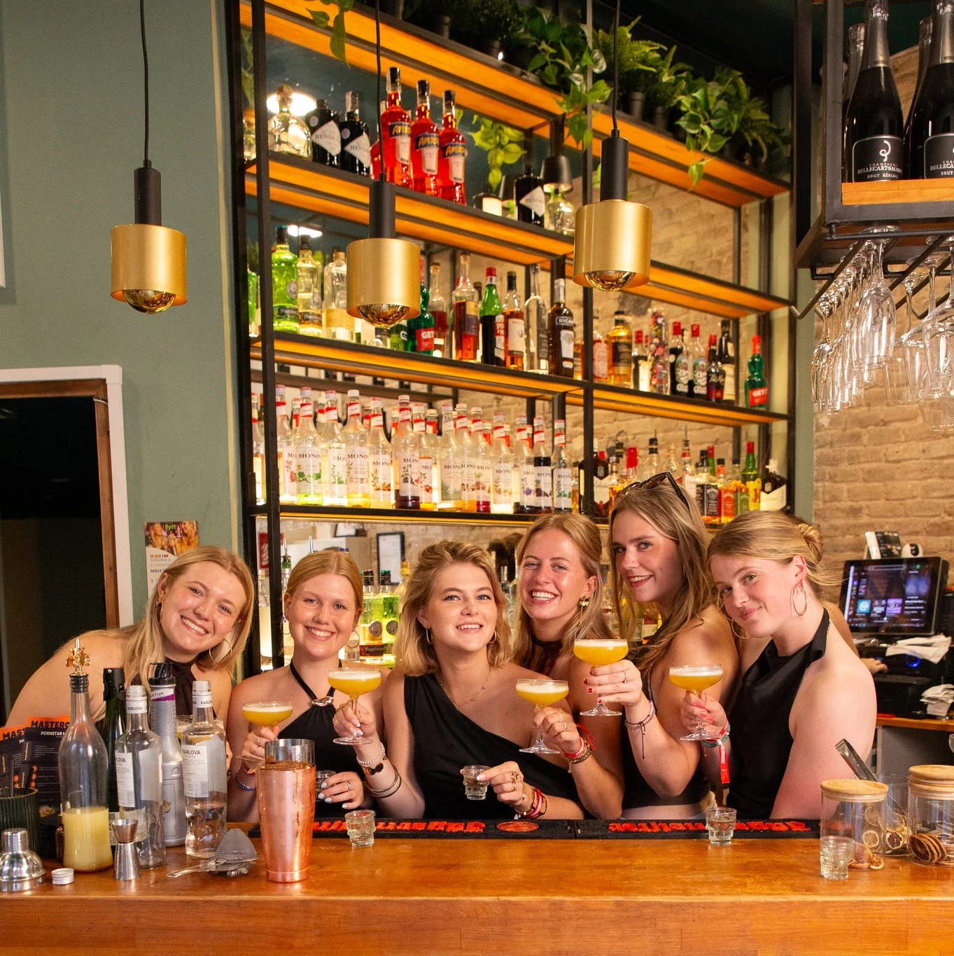 groep-poseert-met-cocktails-achter-de-bar-bij-bpm-bar-eixample-in-barcelona